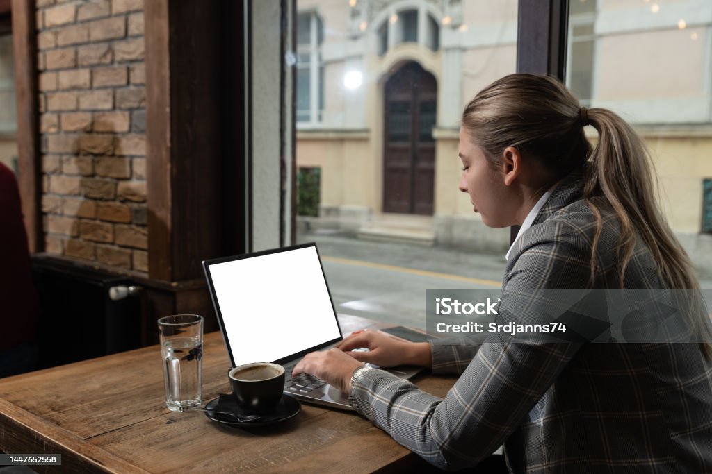 Young business person owner of restaurant or cafeteria bar calculating year tax and profit earnings on the laptop. Freelancer working in the coffee shop on new project. Laptop Stock Photo