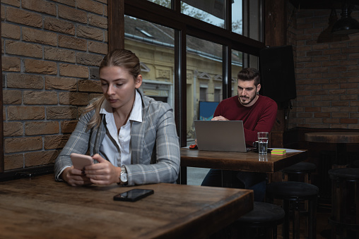 Young business person owner of restaurant or cafeteria bar calculating year tax and profit earnings on the laptop. Freelancer working in the coffee shop on new project.