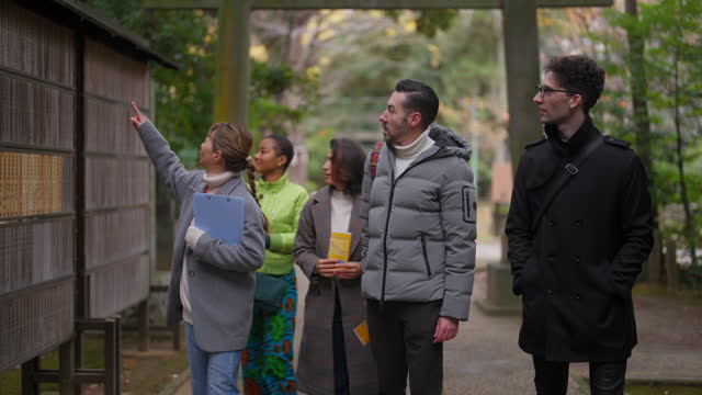 Tourist guide guiding group of multiracial friends to shrine and teaching them about shrine