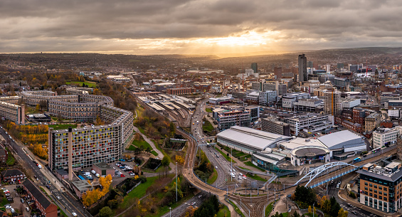 Sheffield, UK - December 6, 2022.  An aerial panorama of Sheffield city centre skyline at sunset with Ponds Forge international swimming pool and Park Hill Estate buildings prominent