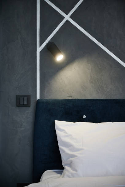istock Elegant dark bed and hanging soft light against gray wall with geometric pattern. 1447657581