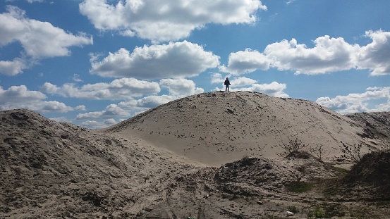 a lonely man stands on a dune against the sky