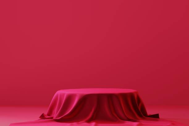 istock Cylinder podium covered with red cloth on viva magenta background. Premium empty fabric pedestal for product display. 1447658118
