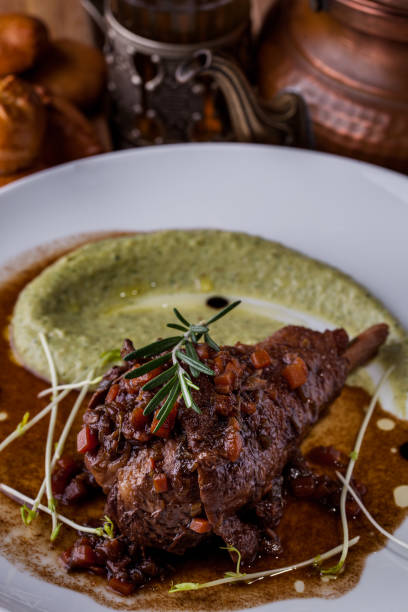 istock Fried lamb on the bone with sauce, rosemary, young shoots, pepper on a white plate. Vertical orientation 1447660774