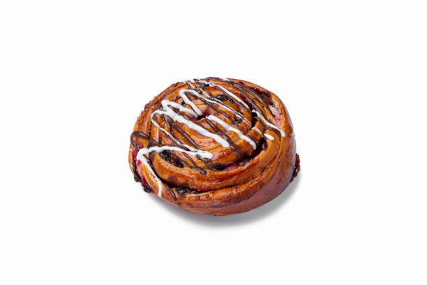 istock Sweet bun with currants, white and chocolate icing on a white plate, close-up. Horizontal orientation 1447663903