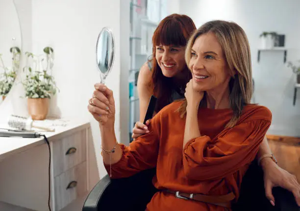 Salon, hairdresser and mirror with a woman customer looking at her reflection with a stylist after haircare or a new hairstyle.