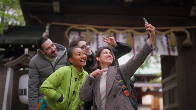 Group of multiracial friends visiting shrine and enjoying taking selfies