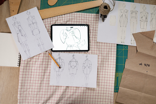 High angle view of clothing sketches on papers and digital tablet in a design studio.