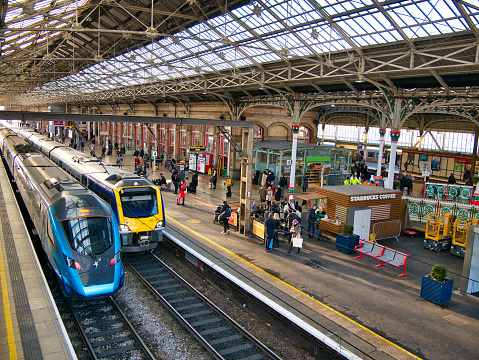England UK. An electric powered train passes through the British Rail station. It is a sunny day . There are no visible people in the picture.