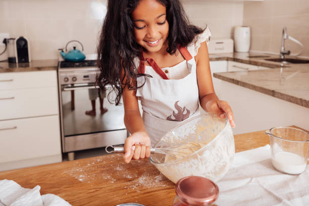 istock Smiling girl in apron mixing dough while standing in the kitchen 1447668285