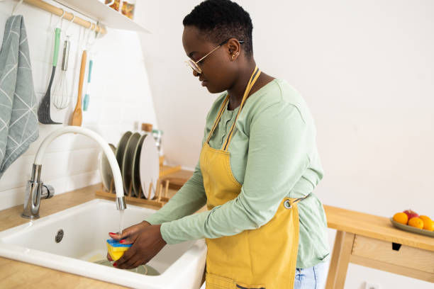 istock African American young woman doing dishes at her kitchen 1447669041