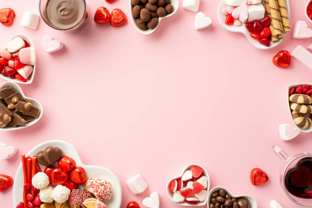 concepto de san valentín. foto de vista superior de platillos en forma de corazón con dulces y vasos con bebida sobre fondo rosa claro aislado con espacio vacío en el medio - valentine candy fotografías e imágenes de stock