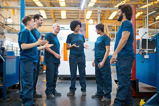 Group of blue-collar workers talking during break in factory.