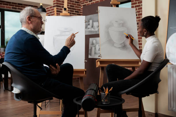 istock Senior painter teacher explaining sketching lesson to young student 1447673658