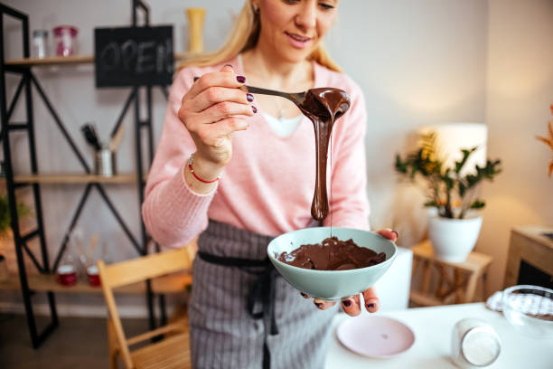 Woman prepares chocolate to fill donuts