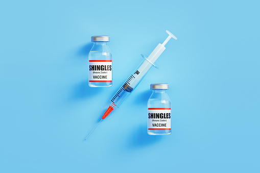 Shingles vaccines and syringe forming percentage sign on blue background, Horizontal composition with copy space. Vaccine efficacy concept.