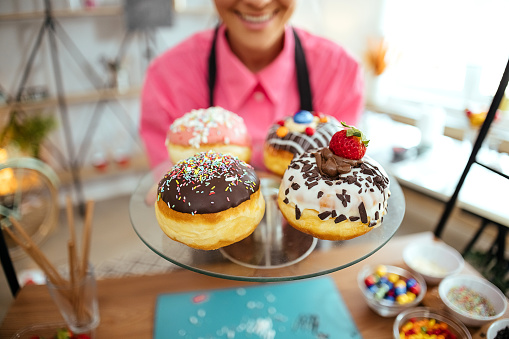 Young woman holding a plate full of tasty doughnuts