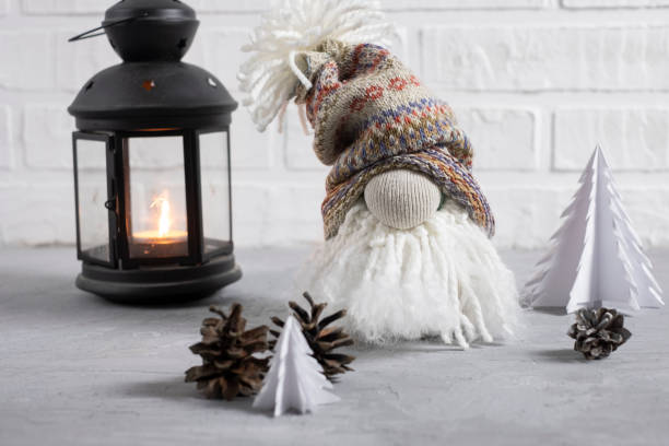 istock A small gnome in a cap with a bubo, beard and a big nose with a flashlight, Christmas tree candles and cones. Decor for christmas in scandinavian style 1447677006