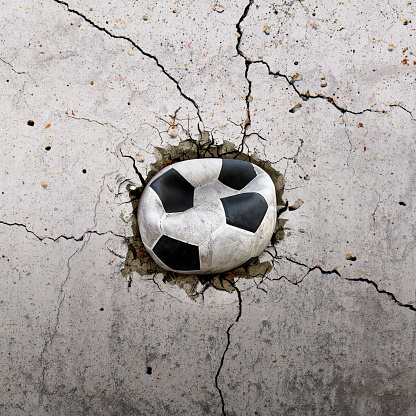 Old soccer ball flying through the wall with cracks
