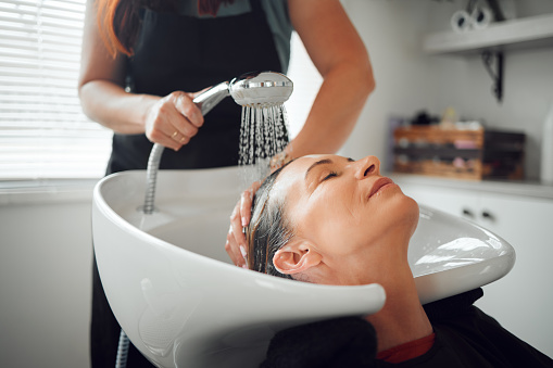 A woman salon, hairdresser cleaning hair in sink and relax after haircare treatment for selfcare wellness. Professional hair stylist, beautician washing and styling lady hairstyle luxury beauty salon