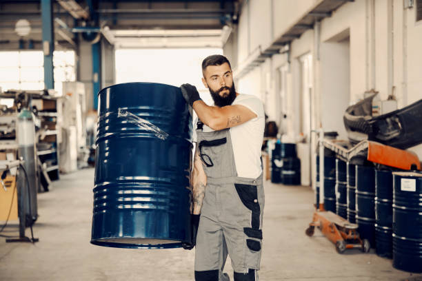 An industry worker carry barrel with oil in facility.