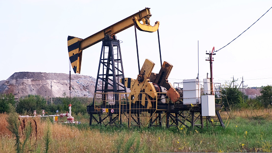 Industrial oil production industry, derrick pumps oil outdoors in the field on the oil platform. The concept of the economy, production and extraction of oil, environmental pollution, fuel, petroleum.
