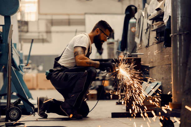 A metallurgy worker kneeling and grinding metal and iron in facility. A heavy industry worker kneeling and grinding metal parts in facility. metal stud stock pictures, royalty-free photos & images