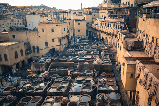 Fes, Morocco – November 19, 2022: Men working at Chouwara Leather traditional tannery in ancient medina of Fes El Bali, Morocco, Africa.
