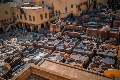 Fes, Morocco – November 19, 2022: Men working at Chouwara Leather traditional tannery in ancient medina of Fes El Bali, Morocco, Africa.