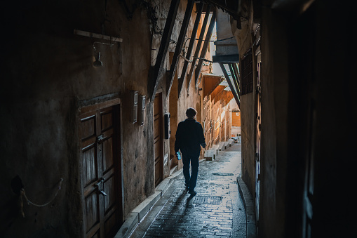 Fez, Morocco – November 19, 2022:  Silhouette of Local Man Walking in Back Alley of  Medina of Fez,  Morocco, Africa.