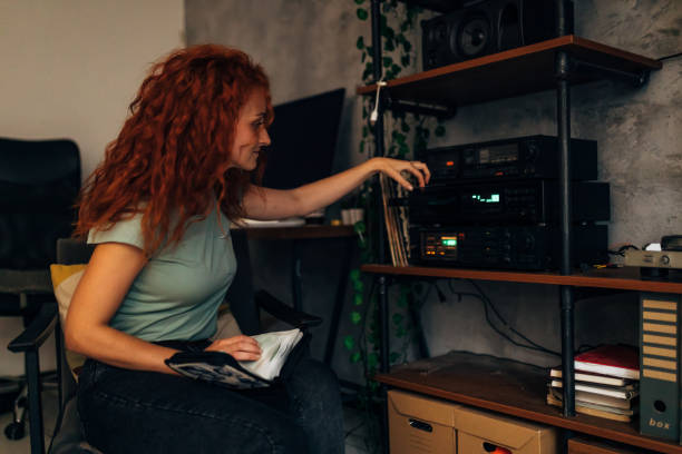 une femme millénaire souriante écoute de vieux cd de musique - home  audio photos et images de collection