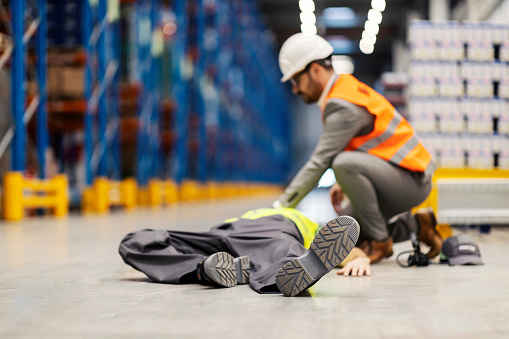 An unconscious storage worker lying while supervisor trying to give him first aid.