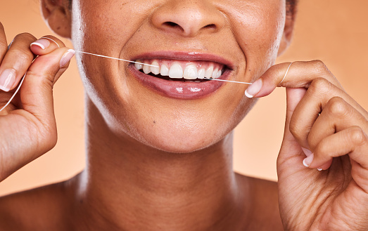 Woman, hands and teeth with smile for dental floss, skincare or personal hygiene against a studio background. Closeup of female smiling and flossing in cosmetics for oral, mouth or gum care treatment