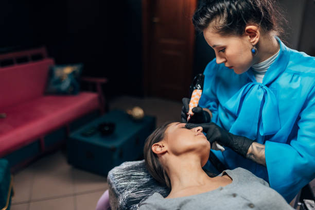 istock A focused beautician  with protective gloves carefully tattoos a woman’s eyebrows 1447691935