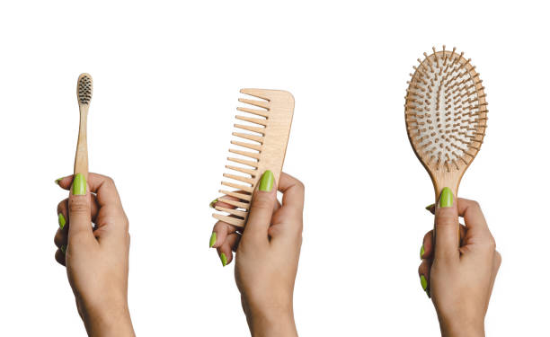 Woman hand holding eco friendly set of hairbrush, comb and toothbrush made of bamboo. Sustainability and eco friendly bathroom accessories stock photo