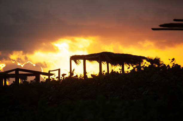 A silhouette of a beach hut with a dramatic sky and sun rise in the backdrop