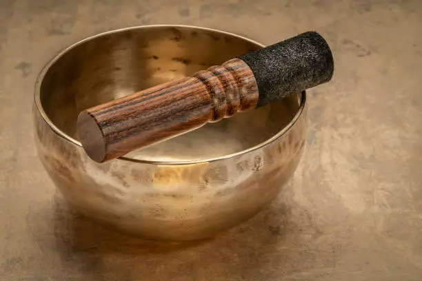 handmade Tibetan singing bowl with a mallet on a textured bark paper, sound therapy for healing, relaxation and meditation
