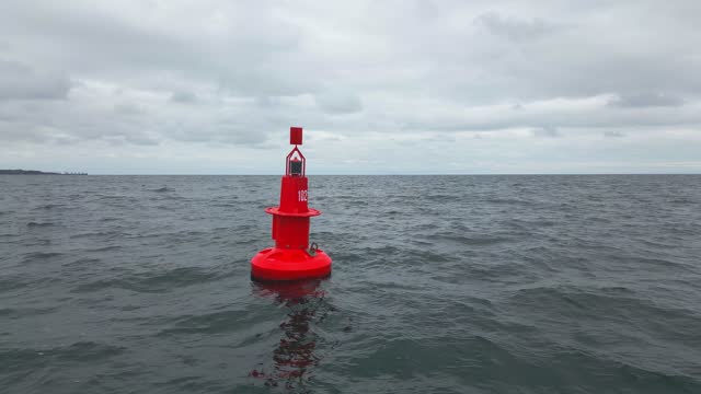 Red Navigational buoy in sea with clouds slow motion
