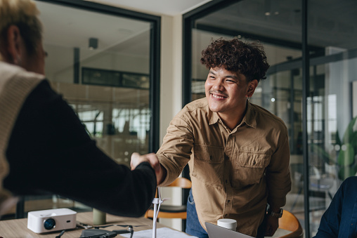 Two business people shaking hands during a meeting in the boardroom