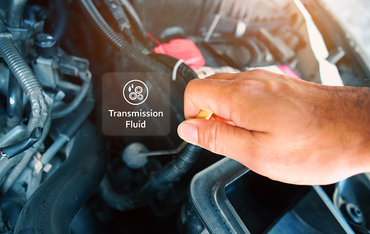 Check the transmission fluid level and gear oil deterioration by a mechanic with transparent gear oil warning symbols on center, auto maintenance service concept