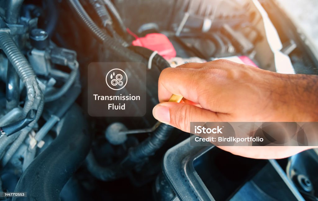 Check the transmission fluid level and gear oil deterioration by a mechanic with transparent gear oil warning symbols on center Check the transmission fluid level and gear oil deterioration by a mechanic with transparent gear oil warning symbols on center, auto maintenance service concept Liquid Stock Photo