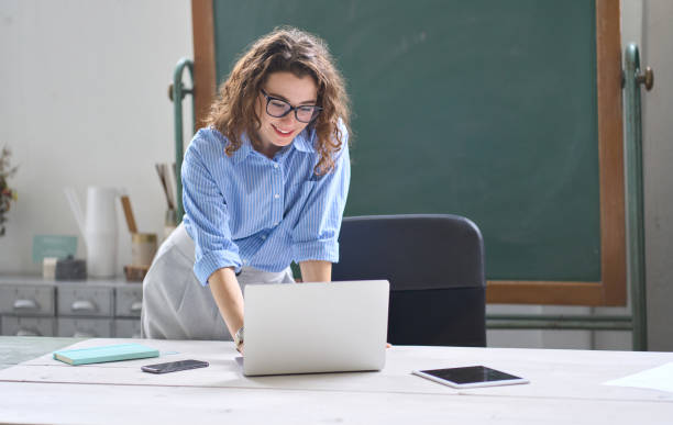 istock Young woman school teacher, online tutor standing at desk teaching remote class. 1447713012