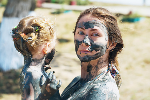 Mum and daughter take treatment mud treatments outside