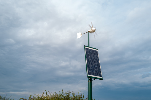 Rural solar powered wind turbine seen quickly spinning helping to provide clean energy to a nearby home.