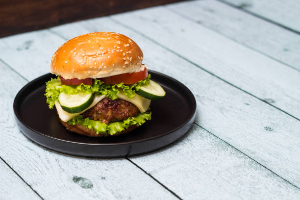 istock Burger in bun with beef meat and cheese, served on black plate 1447714422