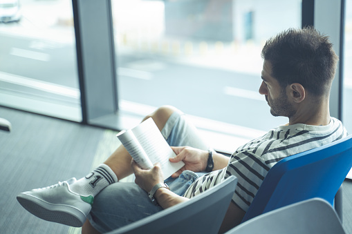 Young man reading book at the airport