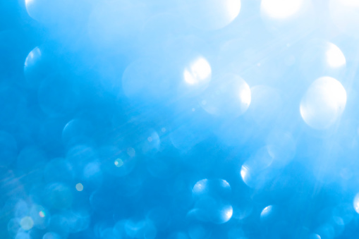 An abstract of a blue bokeh bubble background with lens flare.