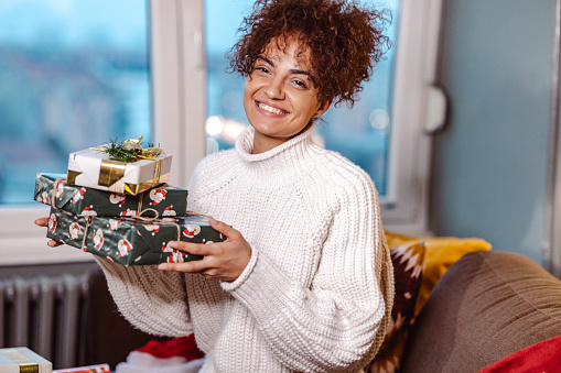 Shot of a young woman with holding Christmas presents and smiling