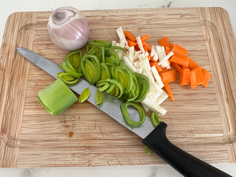 Using Chinese cleaver to slice scallions on Asian style cutting board