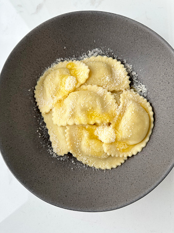 stuffed ravioli with parmesan cheese on gray plate